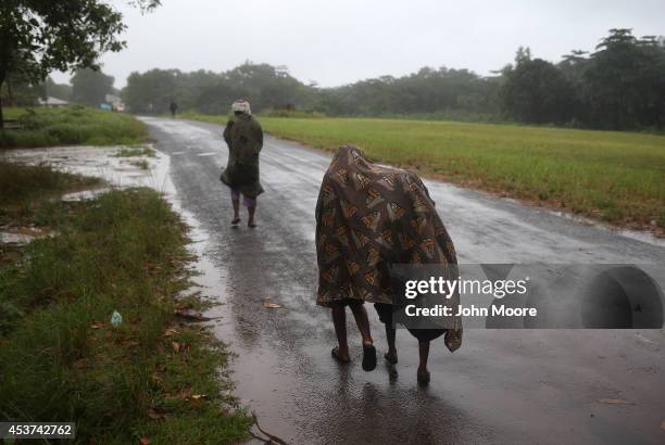 Hanah Siafa walks in the rain with her children Josephine and Elija while waiting to enter the new Doctors Without Borders , Ebola treatment center...