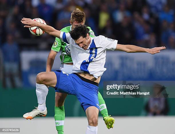 Dominik Stroh-Engel of Darmstadt jumps for a header with Robin Knoche of Wolfsburg during the DFB Cup first round match between SV Darmstadt 98 and...