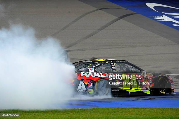 Jeff Gordon, driver of the Axalta Chevrolet, celebrates with a burnout after winning the NASCAR Sprint Cup Series Pure Michigan 400 at Michigan...