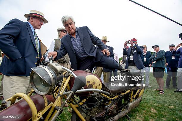 Entertainer Jay Leno gets on a 1930 Bohmerland motorcycle during the 2014 Pebble Beach Concours d'Elegance in Pebble Beach, California, U.S., on...