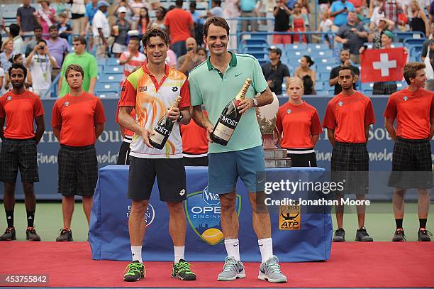 Roger Federer of Switzerland poses with David Ferrer of Spain holding bottles of Moët & Chandon Champagne after winning a final match on day 9 of the...