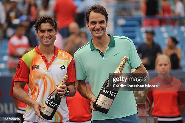 Roger Federer of Switzerland poses with David Ferrer of Spain holding bottles of Moët & Chandon Champagne after winning a final match on day 9 of the...