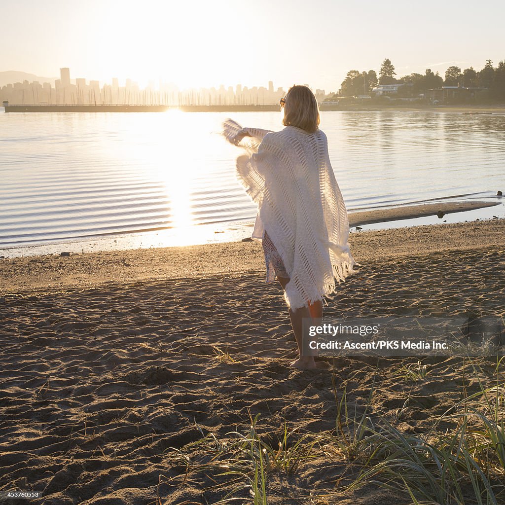 Woman throwing shawl around herself at beach