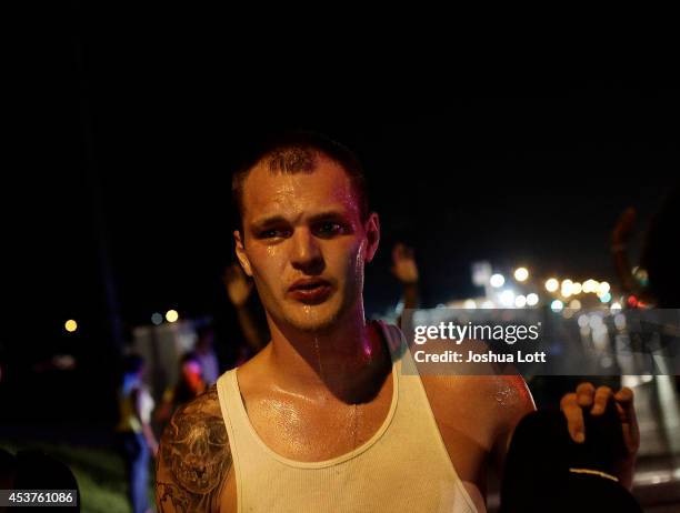 Man reacts after being overcome by tear gas used by police at a protest of the death of Michael Brown August 17, 2014 in Ferguson, Missouri. Tensions...