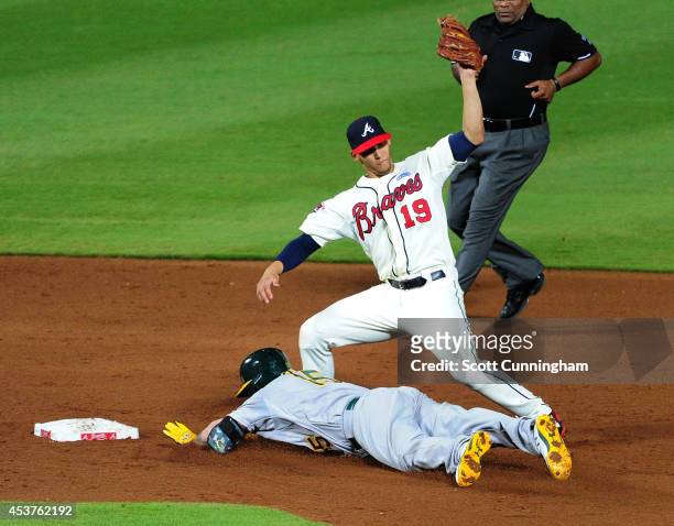 Jonny Gomes of the Oakland Athletics dives safely in to second base against Andrelton Simmons of the Atlanta Braves during the sixth inning at Turner...