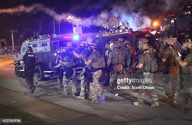 Police advance while sending a volley of tear gas toward demonstrators protesting the killing of teenager Michael Brown on August 17, 2014 in...