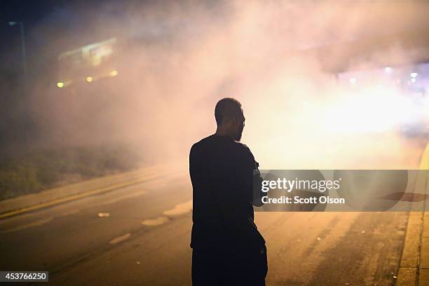 Demonstrator protesting the killing of teenager Michael Brown by a Ferguson police officer stands in a cloud of tear gas after the protest was...