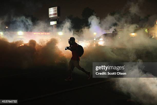 Person runs through a clowd of tear gas that police launched at demonstrators protesting the killing of teenager Michael Brown on August 17, 2014 in...