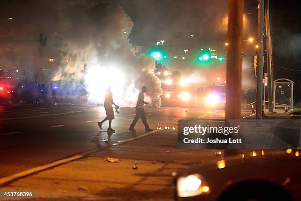 Demonstrators protesting the shooting death of teenager Michael Brown by police walk past tear gas released by police August 17, 2014 in Ferguson,...