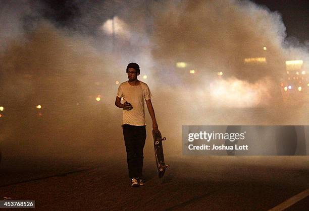 Man with a skateboard protesting the shooting death of teenager Michael Brown by police walks away from tear gas released by police August 17, 2014...