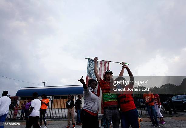 Demonstrators protesting the shooting death of teenager Michael Brown by police stand with an american flag August 17, 2014 in Ferguson, Missouri....