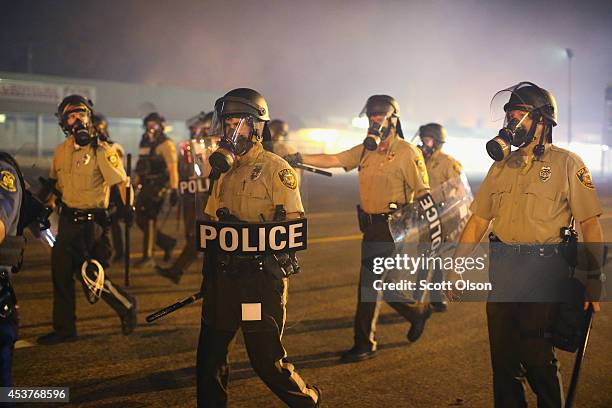Police advance through a cloud of tear gas towards demonstrators protesting the killing of teenager Michael Brown on August 17, 2014 in Ferguson,...