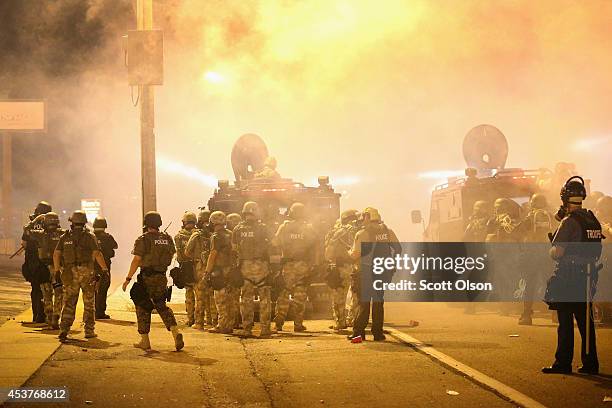 Police advance through a cloud of tear gas toward demonstrators protesting the killing of teenager Michael Brown on August 17, 2014 in Ferguson,...