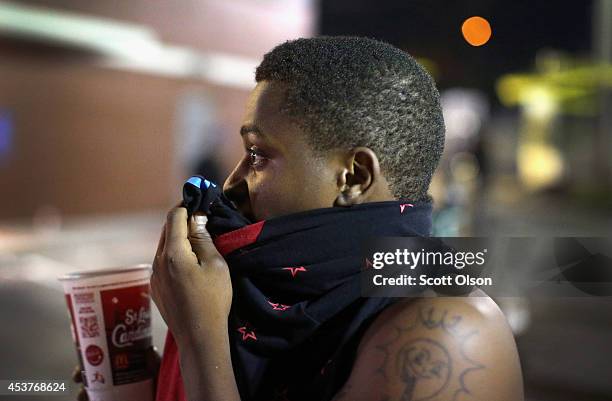 Man covers his face to lessen the affect of tear gas that police launched at demonstrators protesting the killing of teenager Michael Brown on August...