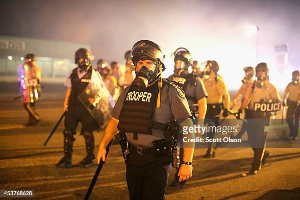 Police advance through a cloud of tear gas toward demonstrators protesting the killing of teenager Michael Brown on August 17, 2014 in Ferguson,...