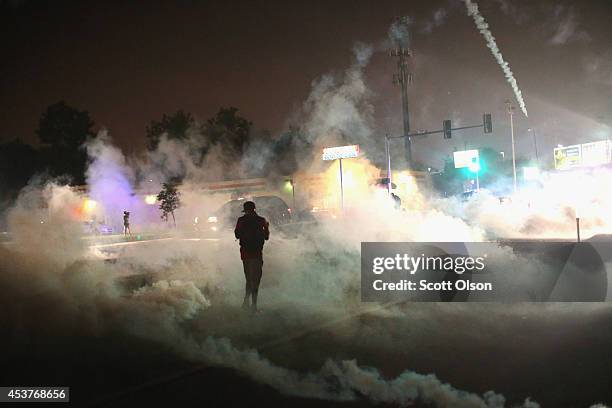 Tear gas fills the street as a demonstrator walks through the haze during protests over the killing of teenager Michael Brown by a Ferguson police...