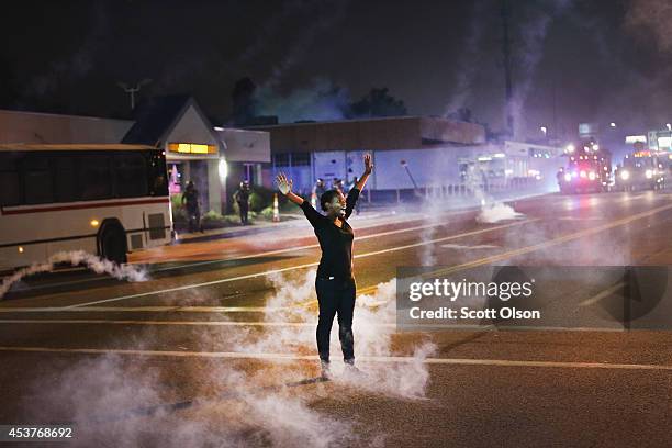 Tear gas reigns down on a woman standing with her arms raised in the street after a demonstration over the killing of teenager Michael Brown by a...