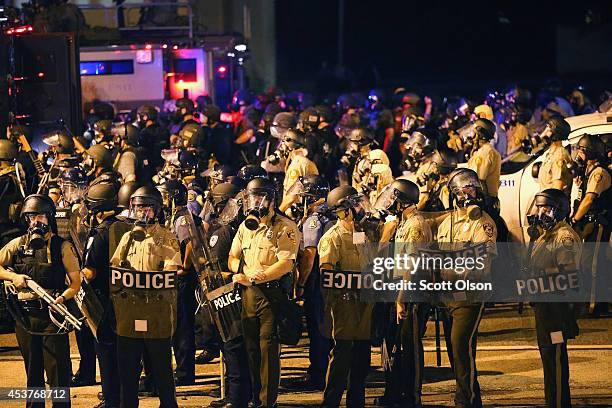 An large group of police officers advance toward demonstrators protesting the killing of teenager Michael Brown on August 17, 2014 in Ferguson,...