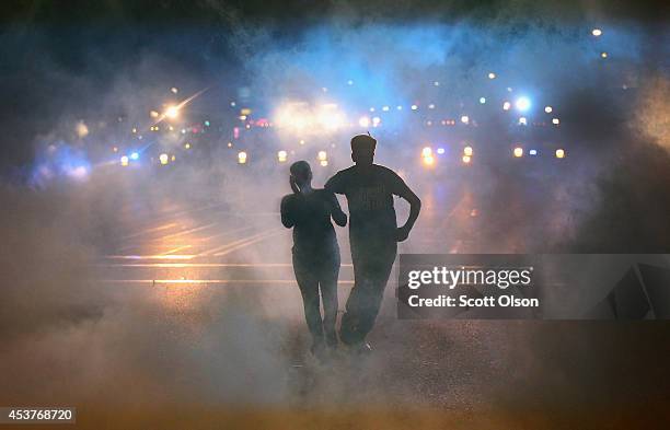 Woman is helped from the street after becoming overcome by tear gas during a demonstration over the killing of teenager Michael Brown by a Ferguson...