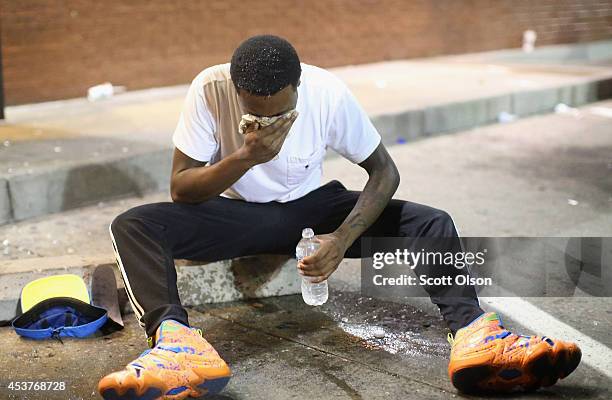 Man is overcome by tear gas which police launched at demonstrators protesting the killing of teenager Michael Brown on August 17, 2014 in Ferguson,...