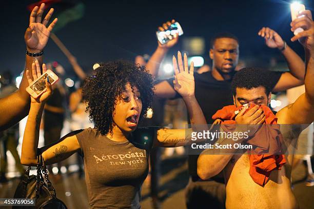 Demonstrators protesting the killing of teenager Michael Brown by a Ferguson police officer try to stand their ground despite being overcome by tear...
