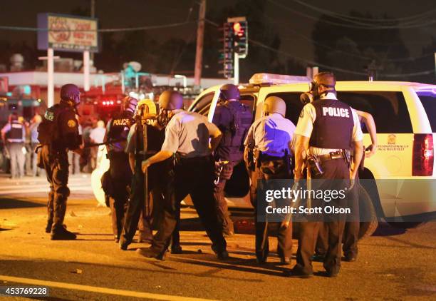 Police take cover after gunshots ring out during a demonstration to protest the killing of teenager Michael Brown turned violent on August 17, 2014...