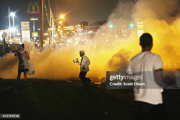 People make their way through the haze as tears gas fills the street during a demonstration over the killing of teenager Michael Brown by a Ferguson...