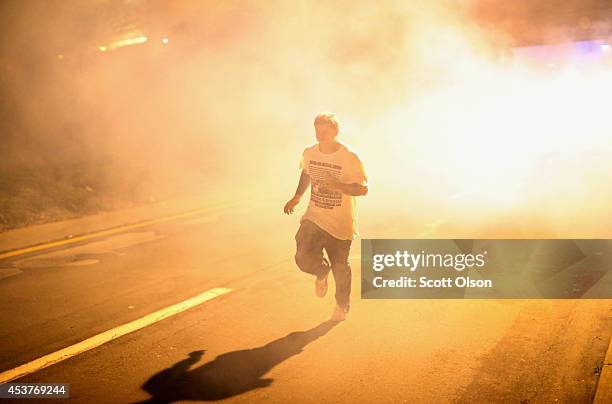 Man runs through the haze as tears gas fills the street during a demonstration over the killing of teenager Michael Brown by a Ferguson police...