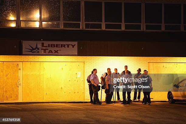 Police stand watch as demonstrators protest the killing of teenager Michael Brown on August 17, 2014 in Ferguson, Missouri. Despite the Brown...