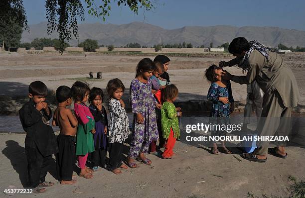 An Afghan health worker administers a polio vaccination to a child during a vaccination campaign on the outskirts of Jalalabad in Nangarhar province...