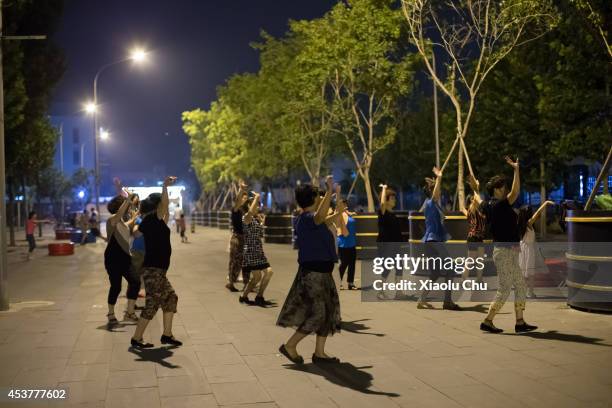 People dance at the plaza of Beijingxiangsu Community at night on August 18, 2014 in Beijing, China.