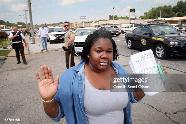 Woman raises her hands as she walks by police shortly after they arrested a demonstrator protesting the killing of teenager Michael Brown on August...