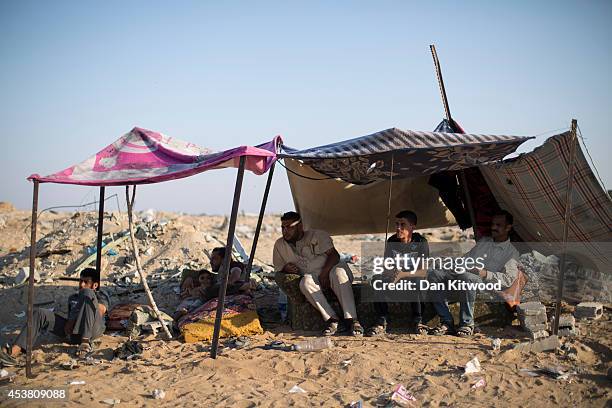 Family sit under a temporary shelter after their home was destroyed, close to the Israeli border on August 14, 2014 in Beit Hanoun, Gaza. A new...