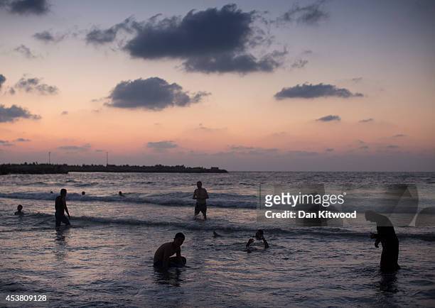 Palestinians cool down in the sea at sunset on August 16, 2014 in Gaza City, Gaza. A five-day ceasefire between Palestinian factions and Israel...