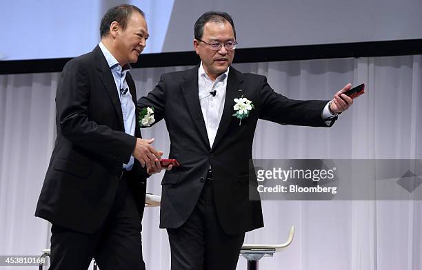 Peter Chou, chief executive officer of HTC Corp., left, is escorted by Takashi Tanaka, president of KDDI Corp., during the unveiling of the HTC J...