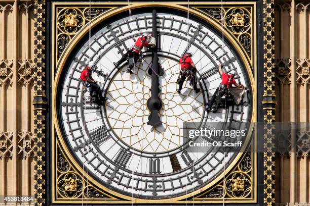 Workers clean the East-facing clock face of the Elizabeth Tower of the Houses of Parliament on August 19, 2014 in London, England. Workers are...