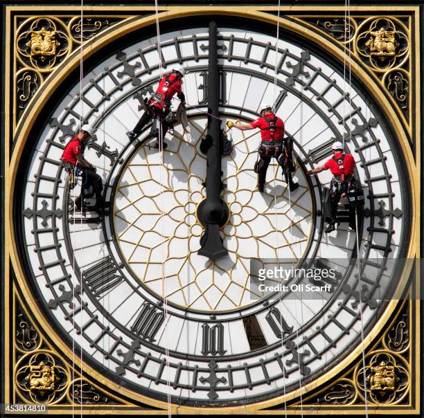 Workers clean the East-facing clock face of the Elizabeth Tower of the Houses of Parliament on August 19, 2014 in London, England. Workers are...