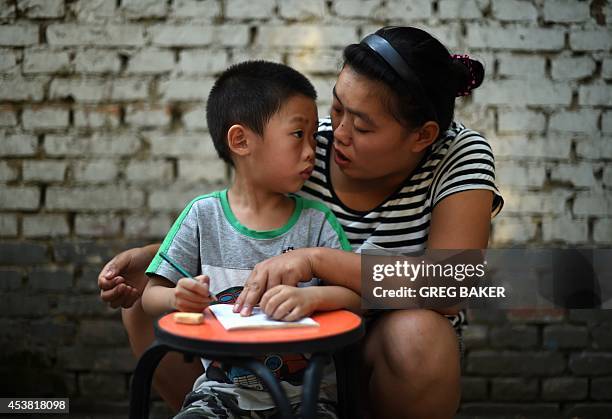 Mother helps her 4-year-old son practice writing Chinese characters in Beijing on August 19, 2014. China's Ministry of Education has said that 400...