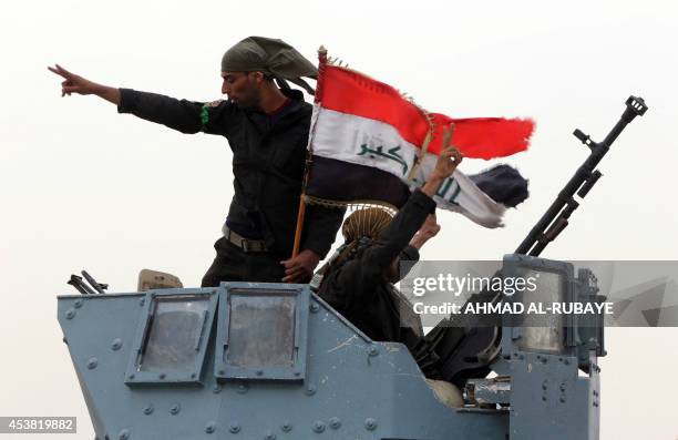 Members of the Iraqi anti-terrorism forces wave the national flag in celebration after securing a checkpoint from Sunni militants in the village of...