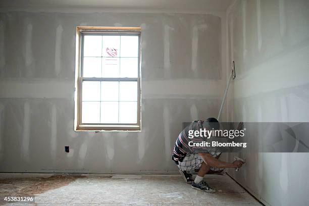 Jose Gutieres uncovers a wall outlet as he finishes drywall in a new home under construction in Peoria, Illinois, U.S., on Tuesday, Aug. 19, 2014....