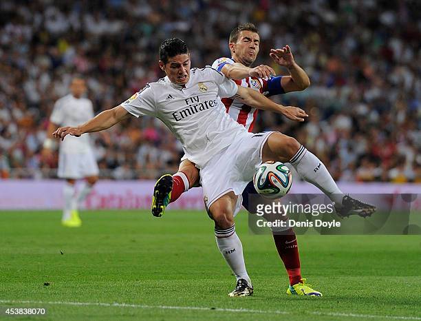 James Rodriguez is tackled by Gabriel Fernandez alias "Gabi" during the Supercopa first leg match between Real Madrid and Club Atletico de Madrid at...