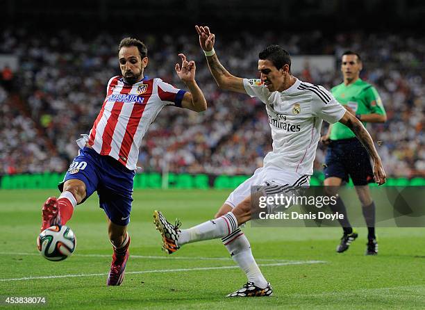 Angel di Maria of Real Madrid shoots past Raul Garcia of Club Atletico de Madrid during the Supercopa first leg match between Real Madrid and Club...