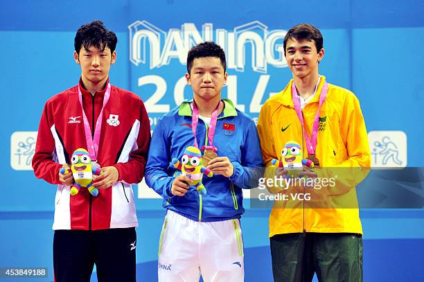 Silver medalist Yuto Muramatsu of Japan, Gold medalist Fan Zhendong of China and Bronze medalist Hugo Calderano of Brazil celebrate on the podium...