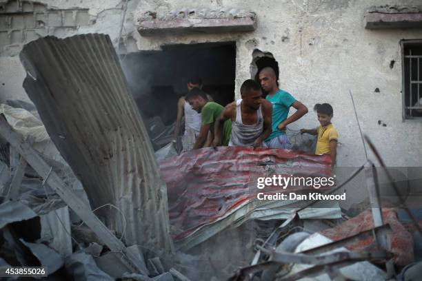 Palestinian men clear debris in an area near the Wafa Hospital on August 14, 2014 in Beit Hanoun, Gaza. A new five-day ceasefire between Palestinian...