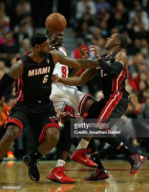 LeBron James of the Miami Heat fouls Loul Deng of the Chicago Bulls as Mario Chalmers defends at the United Center on December 5, 2013 in Chicago,...