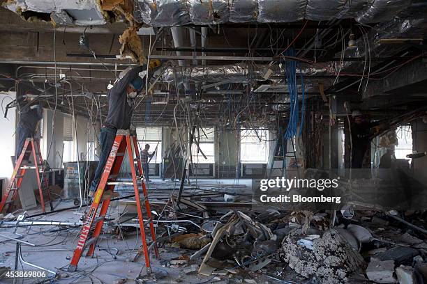 Workers gather debris on the top floor at 75 Rockefeller Plaza during demolition ahead of renovations in New York, U.S., on Monday, Aug. 18, 2014....