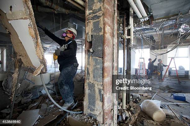 Workers gather debris on the top floor at 75 Rockefeller Plaza during demolition ahead of renovations in New York, U.S., on Monday, Aug. 18, 2014....