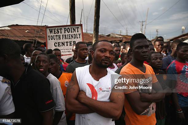 Residents watch as Liberian security forces, part of the country's Ebola Task Force, enforce a quarantine on the West Point slum on August 20, 2014...