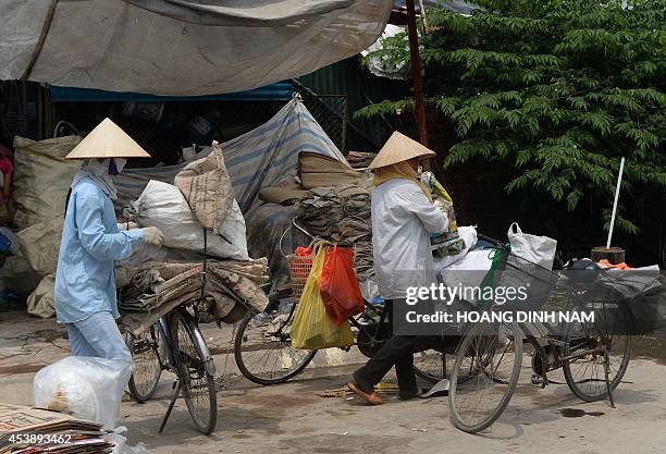 Collectors of recyclable items arrive on bicycles to sell what they collected at a trader's buying point set up near the Keanang buildings ,...