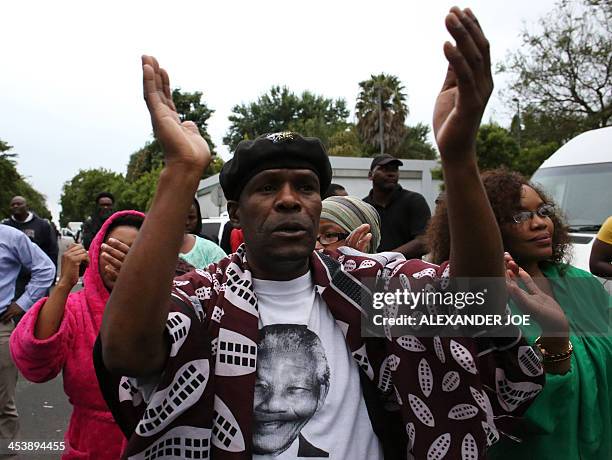 Pëople sing and dance in honour as they pay a tribute to late former South African president Nelson Mandela in Soweto on December 6, 2013. Residents...